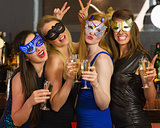 Attractive women wearing masks holding champagne
