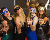 Happy friends wearing masks showing champagne glasses