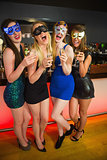 Laughing friends with masks on holding champagne