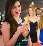 Attractive woman standing in front of her friends holding cocktail