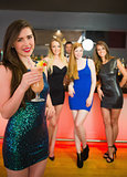 Smiling woman standing in front of of her friends holding cocktail