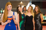 Attractive woman holding cocktail standing in front of her friends