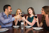 Friends clinking red wine glasses at a bar
