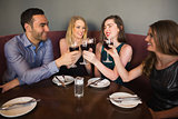 Laughing friends sitting together clinking glasses