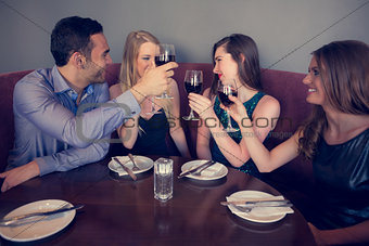 Smiling friends clinking wine glasses