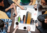 Overhead view of people sitting around table with painted city on sheet