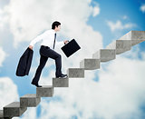 Young businessman climbing grey stairs