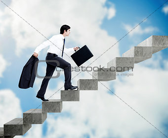 Young businessman climbing grey stairs