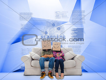 Couple with cartons on head sitting on couch under holographic finger print