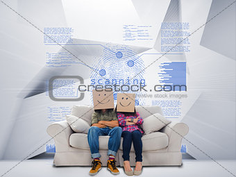 Couple with cartons on head sitting on couch under blue holographic finger print