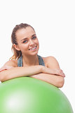 Cheerful young woman supporting herself with a fitness ball