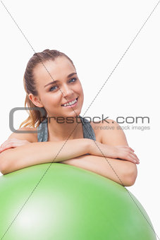 Cheerful young woman supporting herself with a fitness ball