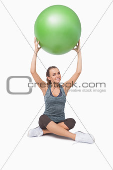 Sporty young woman lifting a green fitness ball