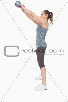 Profile view of ponytailed woman training with a kettle bell