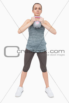 Cute woman training her body with a kettle bell