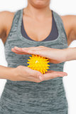 Close up of young woman holding yellow massage ball between her hands