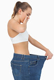 Astonished slim young woman wearing too big jeans