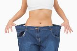 Mid section of young slim woman wearing too big jeans