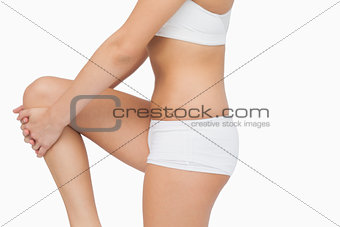 Mid section of young woman stretching her leg