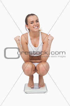 Young woman crouching on a scales