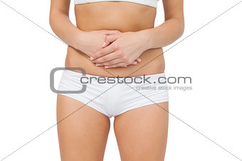 Mid section of woman touching her belly with her hands