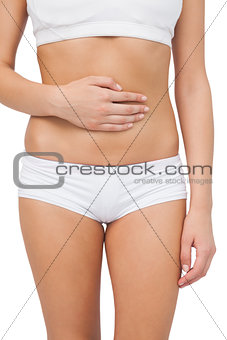 Young slim woman touching her belly with one hand