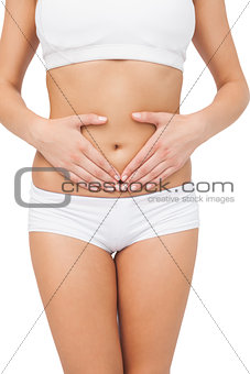 Slim young woman touching her belly with her hands