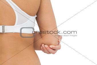 Rear view of young woman touching her injured elbow