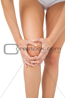 Slim young woman touching her injured knee
