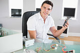 Attractive cheerful computer engineer sitting at desk holding hardware
