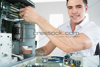 Handsome smiling computer engineer working at open computer