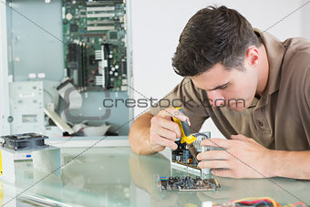 Handsome serious computer engineer repairing hardware with pliers