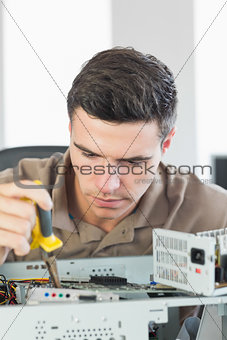 Handsome focused computer engineer repairing open computer