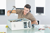 Attractive angry computer engineer destroying computer with hammer