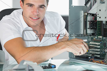 Smiling computer engineer repairing computer with pliers