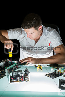 Handsome computer engineer working by night with screw driver
