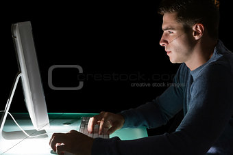 Handsome serious computer engineer looking at computer at night