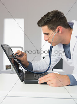 Attractive computer engineer examining laptop with stethoscope