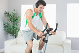Sporty handsome man training on exercise bike listening to music