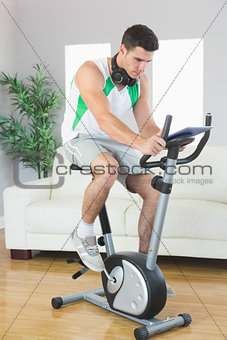 Handsome man training on exercise bike using tablet
