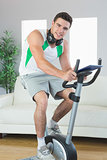 Content handsome man training on exercise bike using tablet