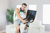 Content handsome man training on exercise bike using laptop