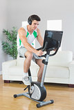Serious handsome man training on exercise bike using laptop