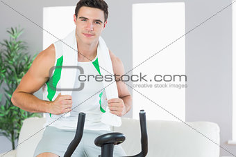 Smiling handsome man training on exercise bike