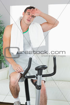 Exhausted handsome man training on exercise bike