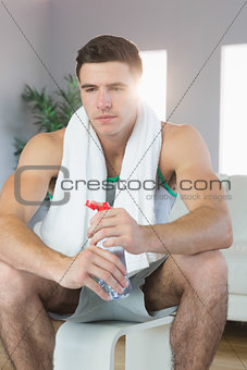 Tired handsome man sitting holding water bottle