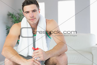 Unsmiling handsome man sitting holding water bottle