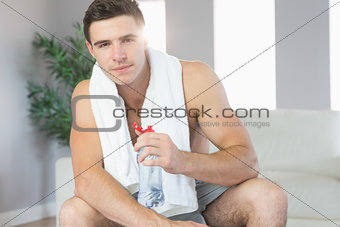 Sexy handsome man sitting holding water bottle