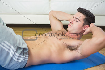 Frowning handsome man doing sit ups