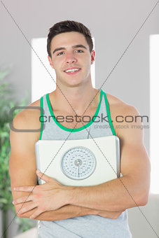 Cheerful handsome man holding scales